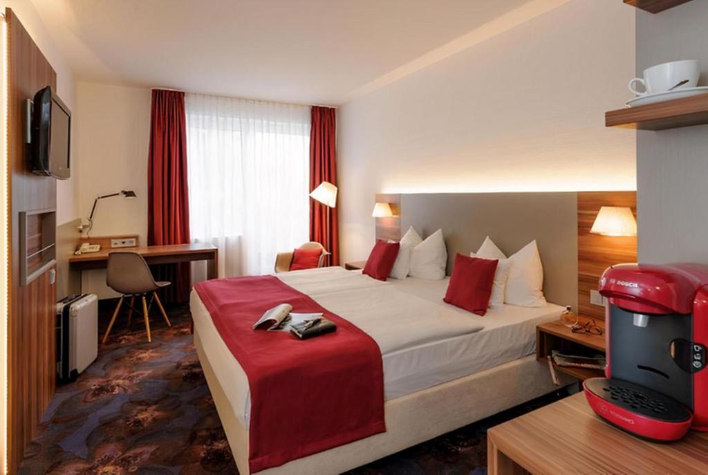 a hotel room with a large bed and a desk at PLAZA INN Regensburg in Regensburg