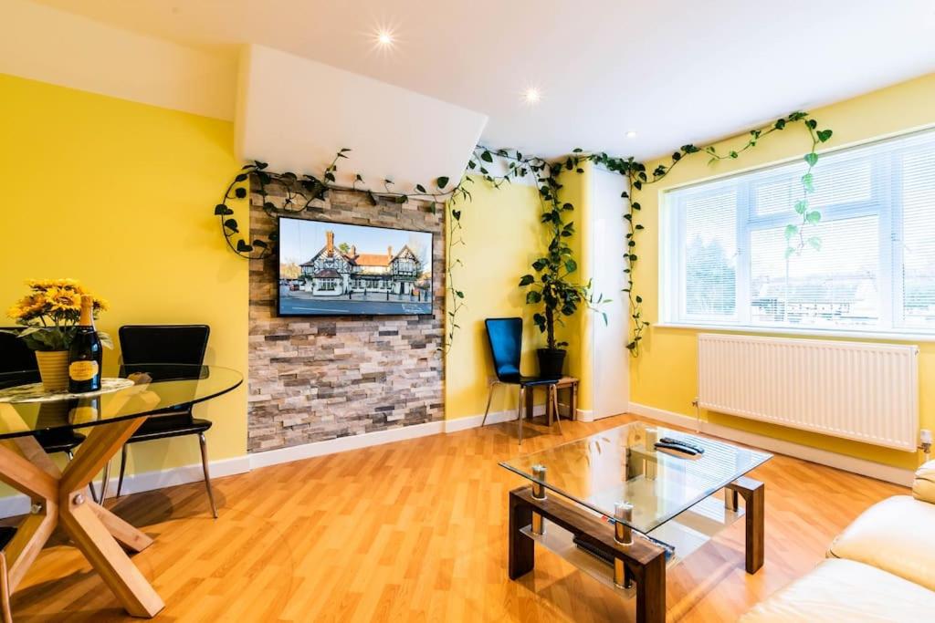 a living room with a glass table and yellow walls at Comfy Apartment 16 Easy access to Central London in Tadworth