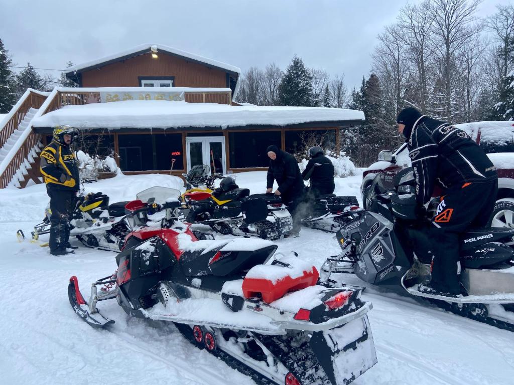 a group of people standing in the snow with their snowmobiles at Madawaska Lodge in Madawaska