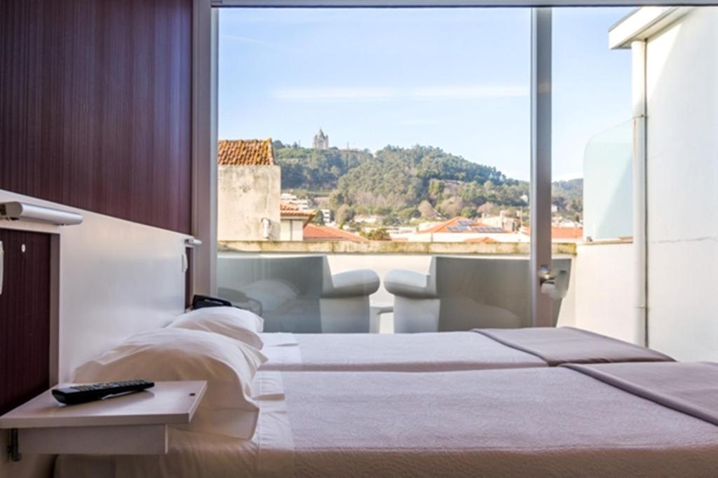 1 dormitorio con 2 camas y ventana grande en Hotel Laranjeira, en Viana do Castelo