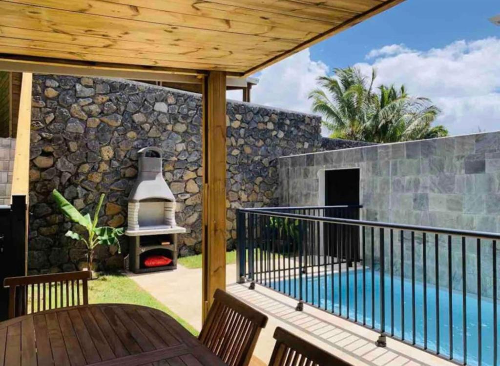 un patio con una pared de piedra y una parrilla al aire libre en Villa Cap Méchant piscine chauffée avril à octobre en Saint-Joseph