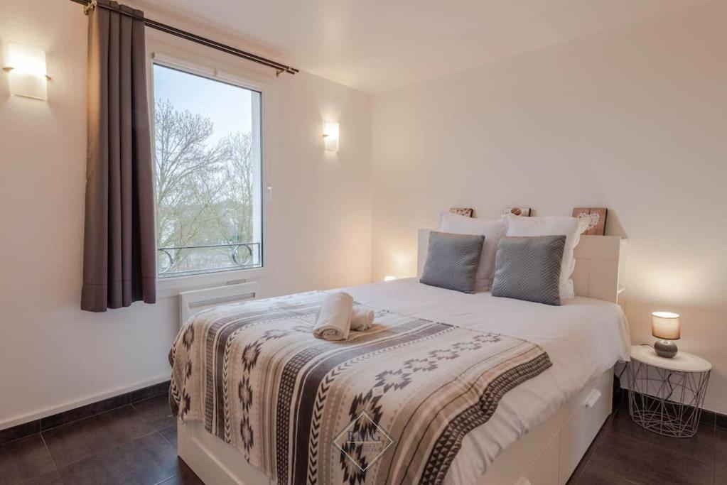 biała sypialnia z dużym łóżkiem i oknem w obiekcie Résidence du Moulin Disneyland BMYGUEST w mieście Magny-le-Hongre