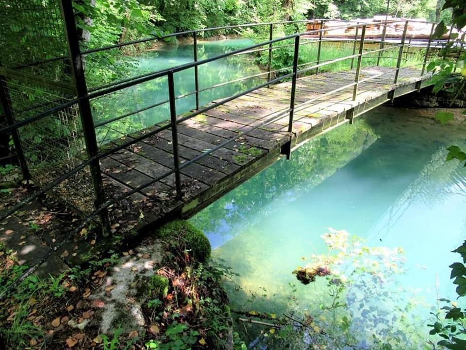 un pont sur une rivière à eau bleue dans l'établissement Chambre d'hôte de la Source Bleue, à Cusance