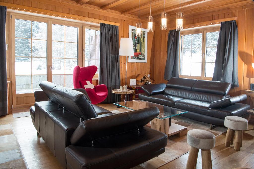 a living room with black leather furniture and windows at Residence for 12 persons Chalet Crestas-Lenzerheide in Lenzerheide