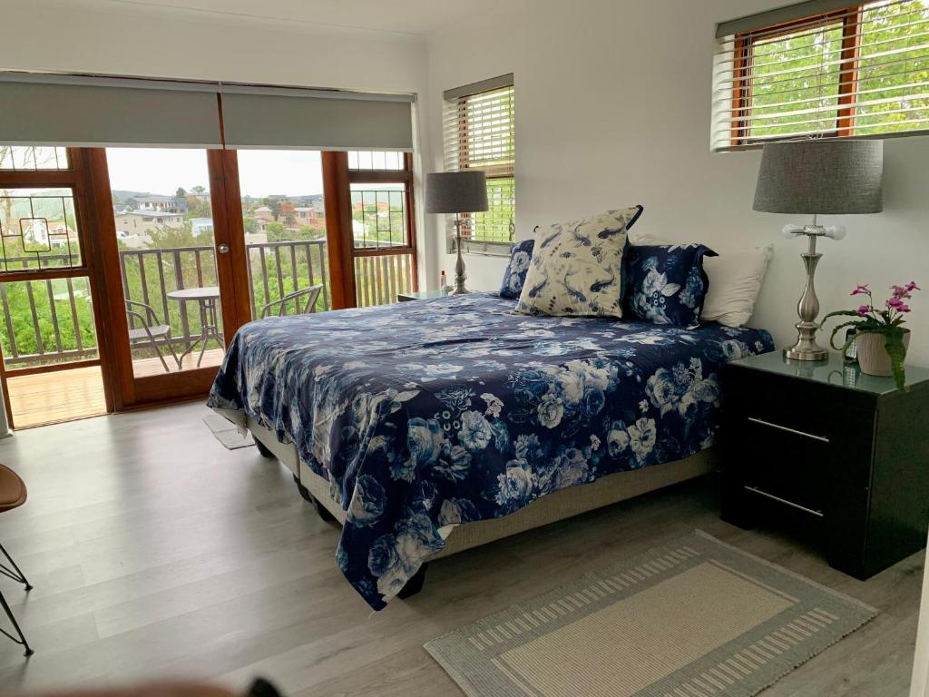a bedroom with a bed with a blue comforter at Kindred Spirit Guest Suites with solar power in Knysna