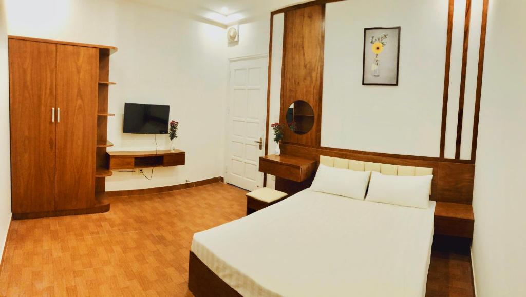 1 dormitorio con 1 cama blanca y TV en Đức Tuân 2 Motel en Hai Phong