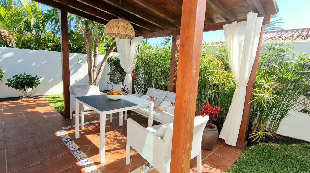 a patio with a white table and chairs and trees at Los Porches D40 By Pride Holiday Rentals in San Bartolomé