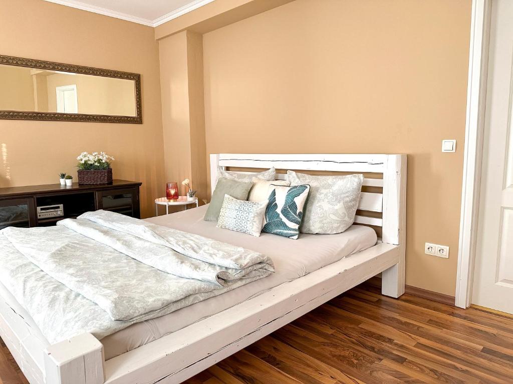 - une chambre dotée d'un lit blanc avec des oreillers et un miroir dans l'établissement Apartement am Schloss Pillnitz, à Dresde