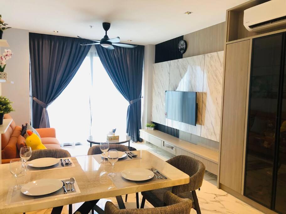 a dining room table with chairs and a television at Lumi Tropicana, PJ-02, Golf View in Petaling Jaya