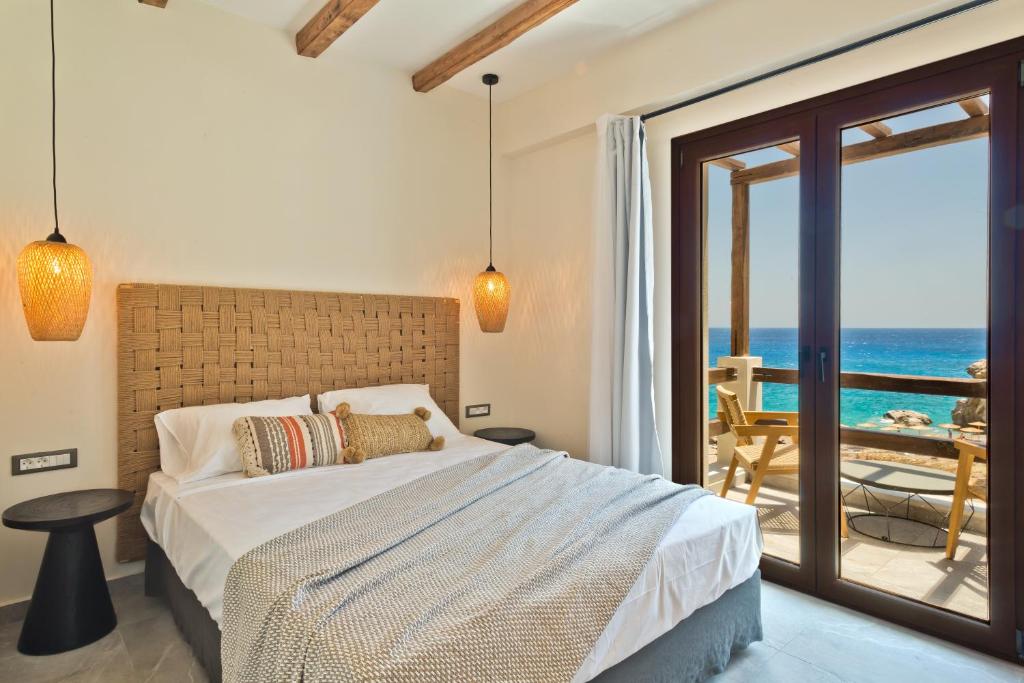 a bedroom with a bed and a view of the ocean at Ypsilos Beach Suites in Kyra Panagia