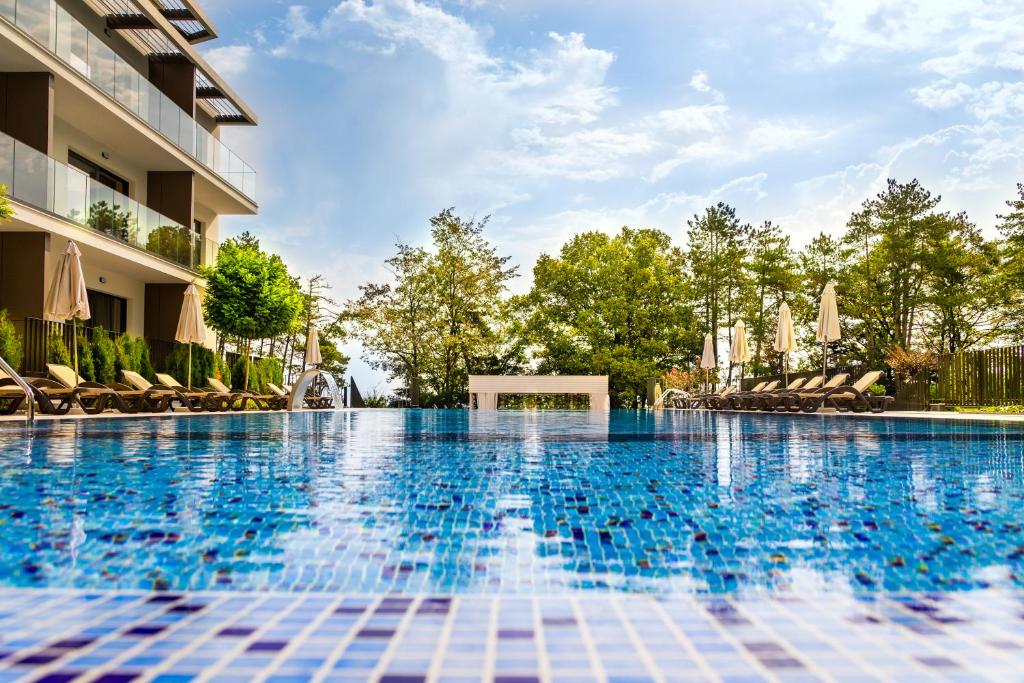 a swimming pool at a hotel with chairs and trees at Open Sea Residence in Byala