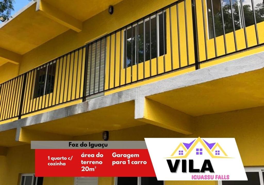 Un bâtiment jaune avec un panneau de vla devant lui dans l'établissement Apartamento Loft encantador com patio, à Foz do Iguaçu