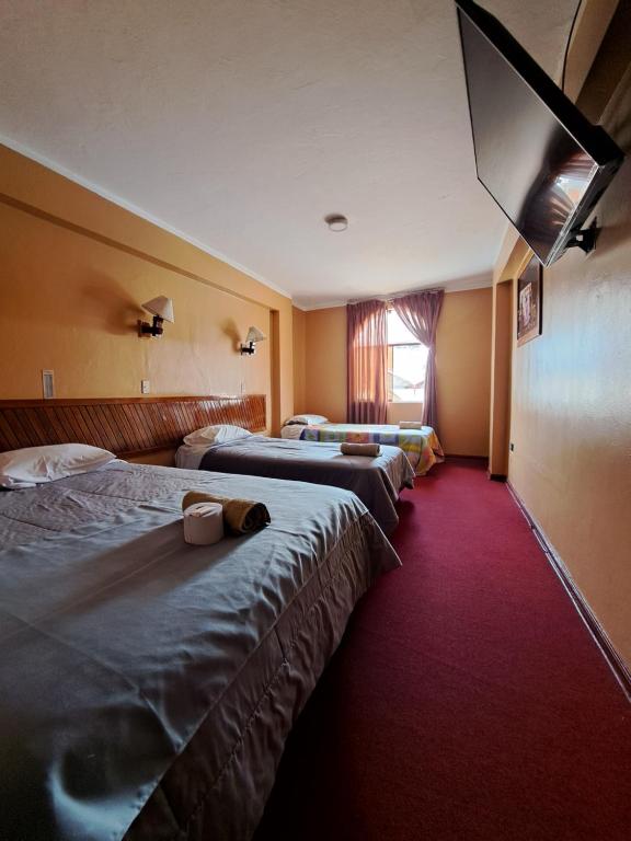 a hotel room with three beds and a window at Hotel la casona in Huaraz