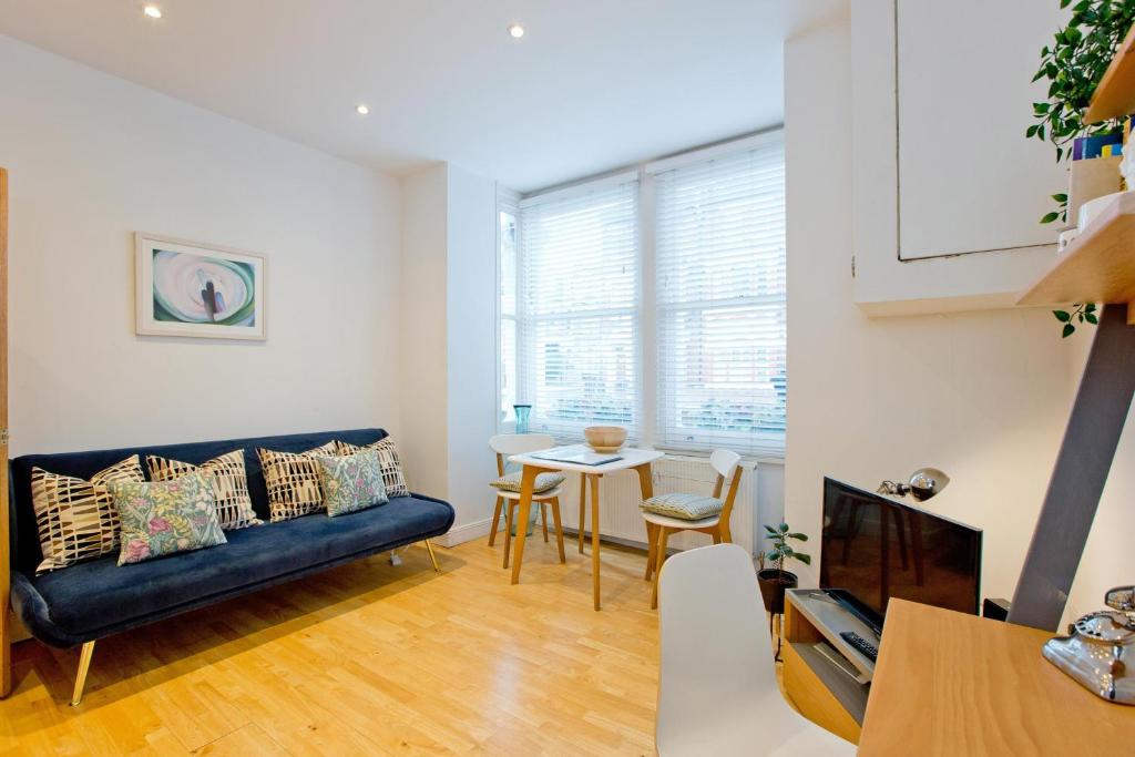Calabria 2 - Cosy apartment في لندن: غرفة معيشة مع أريكة وطاولة