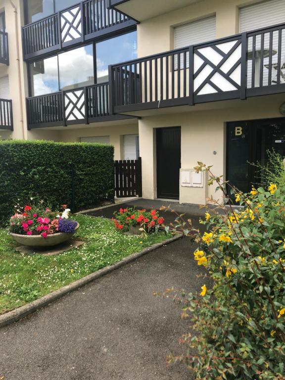a building with a balcony and flowers in a yard at Le Villergeois 5 pers très proche mer in Villers-sur-Mer