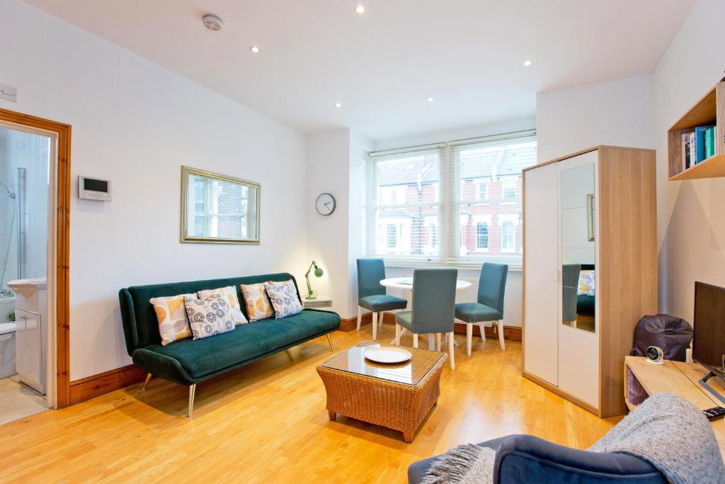 a living room with a green couch and a table at Calabria 4 Comfortable apartment in London