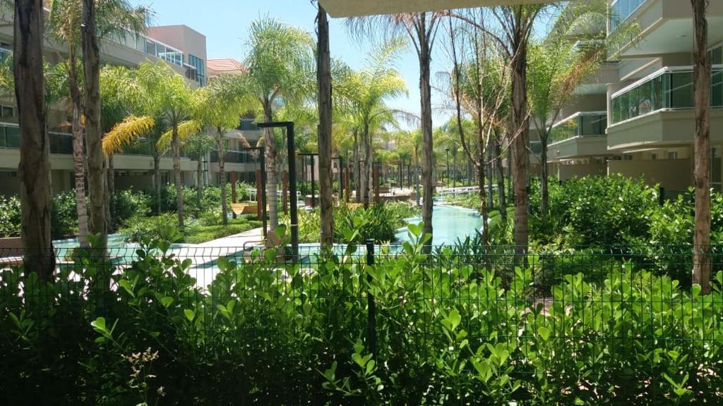 un jardín con piscina frente a un edificio en Barra Garden Happy - Condomínio Barra Village Lakes tipo Resort - Recreio dos Bandeirantes, en Río de Janeiro