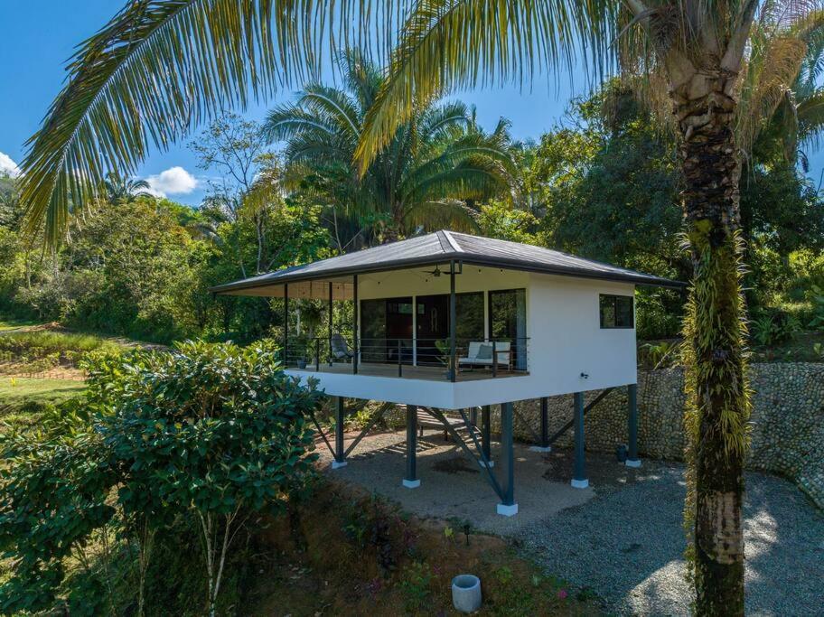 a small white house with a palm tree at The Surf Journey Casita in Uvita