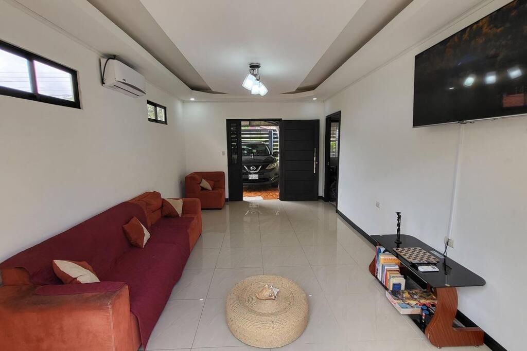 ein Wohnzimmer mit einem roten Sofa und einem TV in der Unterkunft Casa Congo in Golfito