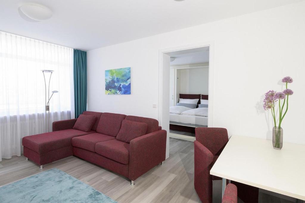 ein Wohnzimmer mit einem roten Sofa und einem Bett in der Unterkunft Huber Living Deluxe 108 in Germering
