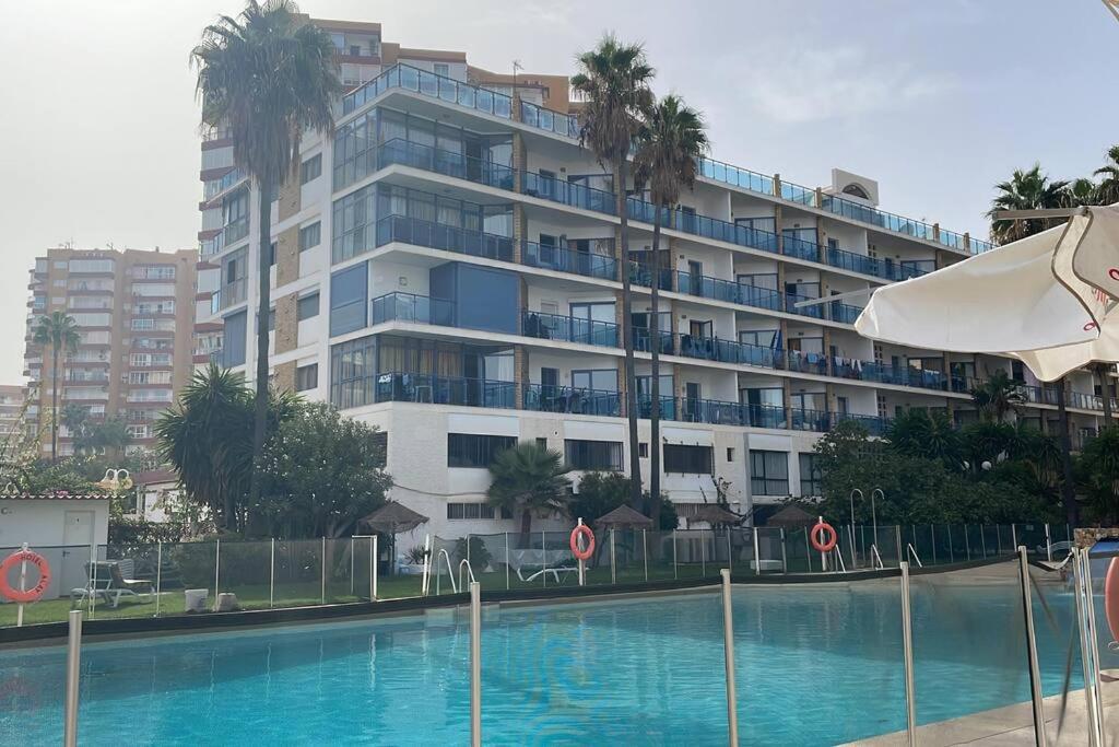 a large apartment building with a swimming pool in front of it at Cozy Renovated Studio located in centre of Benalmadena and Puerto Marina in Benalmádena