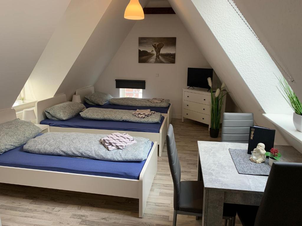 - une chambre mansardée avec 2 lits et une table dans l'établissement Flensburg Zentrum 10 VH DGL, à Flensbourg