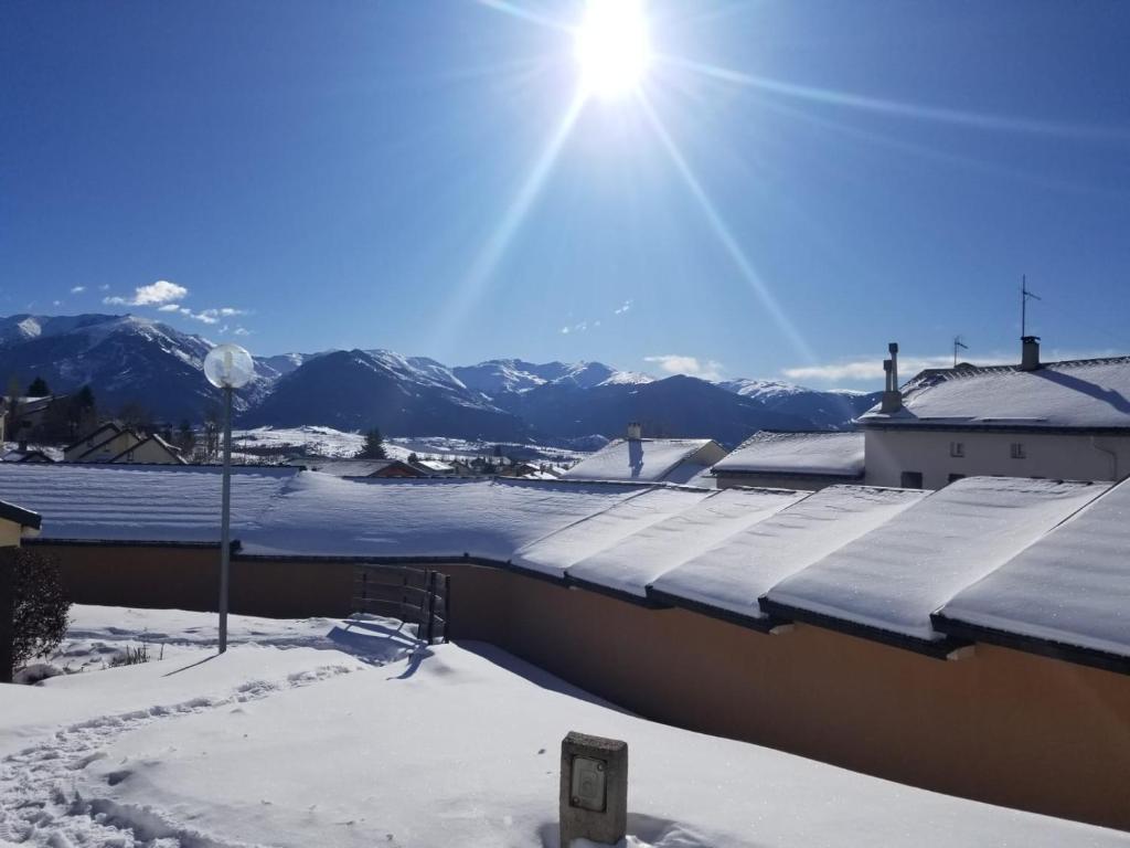 um telhado coberto de neve de um edifício com montanhas ao fundo em Chalet, 5 couchages, wifi, garage, parking gratuit Les Fontanilles Draps et serviettes non fournis em Font Romeu Odeillo Via