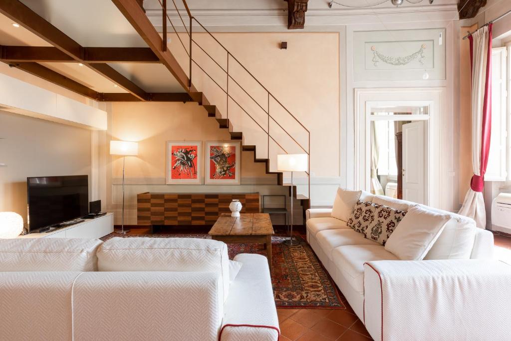 un soggiorno con mobili bianchi e una scala di Palazzo Orsucci Apartment a Lucca