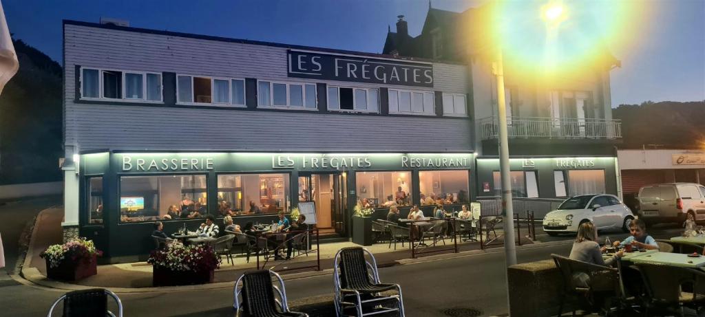 un restaurante con gente sentada en las mesas frente a un edificio en Les Fregates en Veulettes-sur-Mer