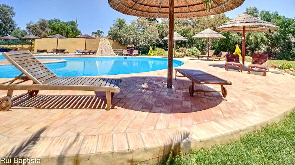 a pool with two chairs and an umbrella at Arrancada 14 in Pêra