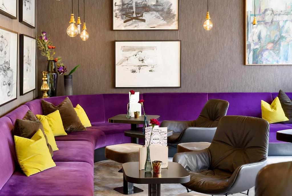 a purple couch in a room with chairs and tables at PLAZA INN Regensburg in Regensburg