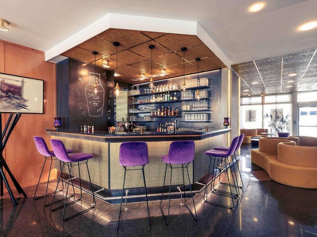 a bar with purple bar stools in a restaurant at PLAZA INN Regensburg in Regensburg