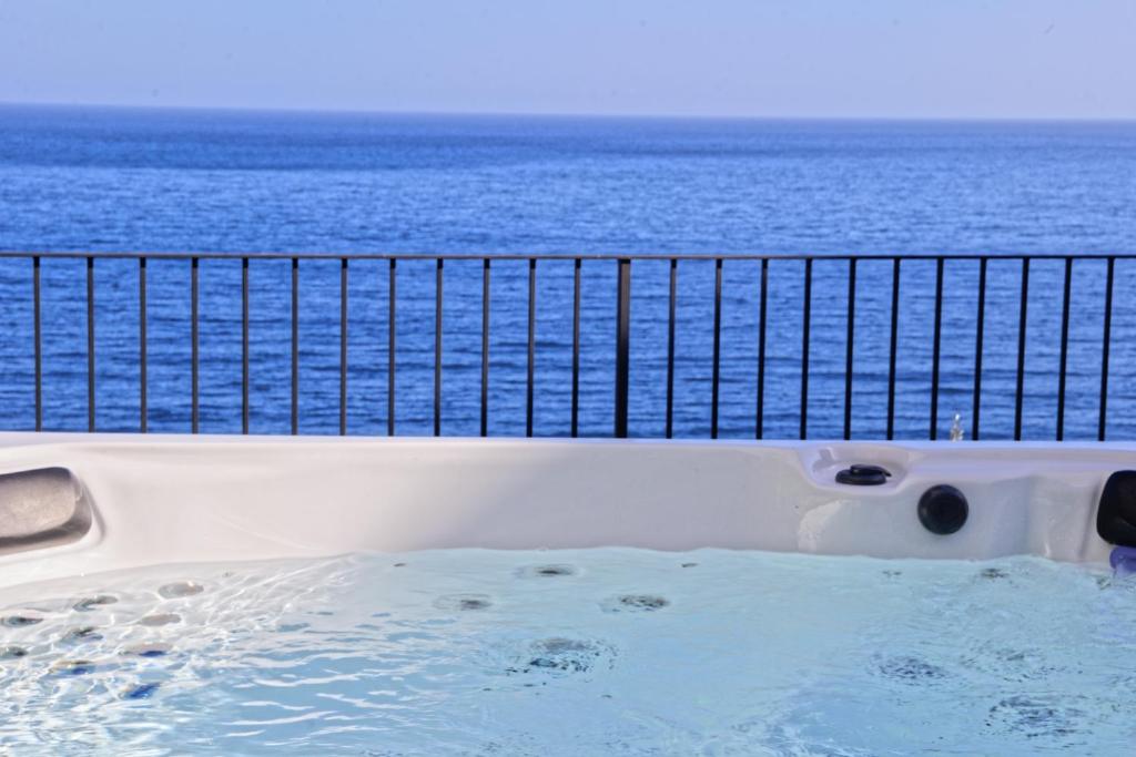 una vasca idromassaggio su un balcone con vista sull'oceano di A Casa Janca a Pozzillo