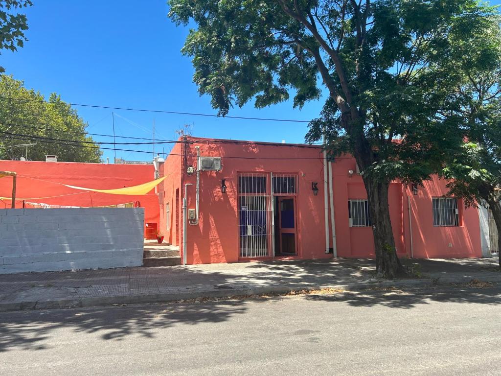 a red building with a tree in front of it at Hostel Parece Mentira in Colonia del Sacramento