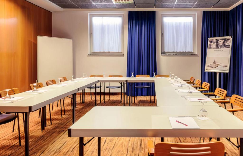a conference room with tables and chairs and a whiteboard at PLAZA INN Regensburg in Regensburg