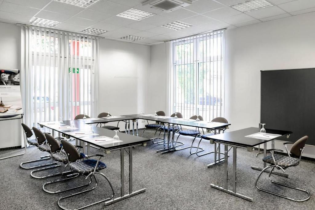 a conference room with tables and chairs and a blackboard at PLAZA INN Regensburg in Regensburg