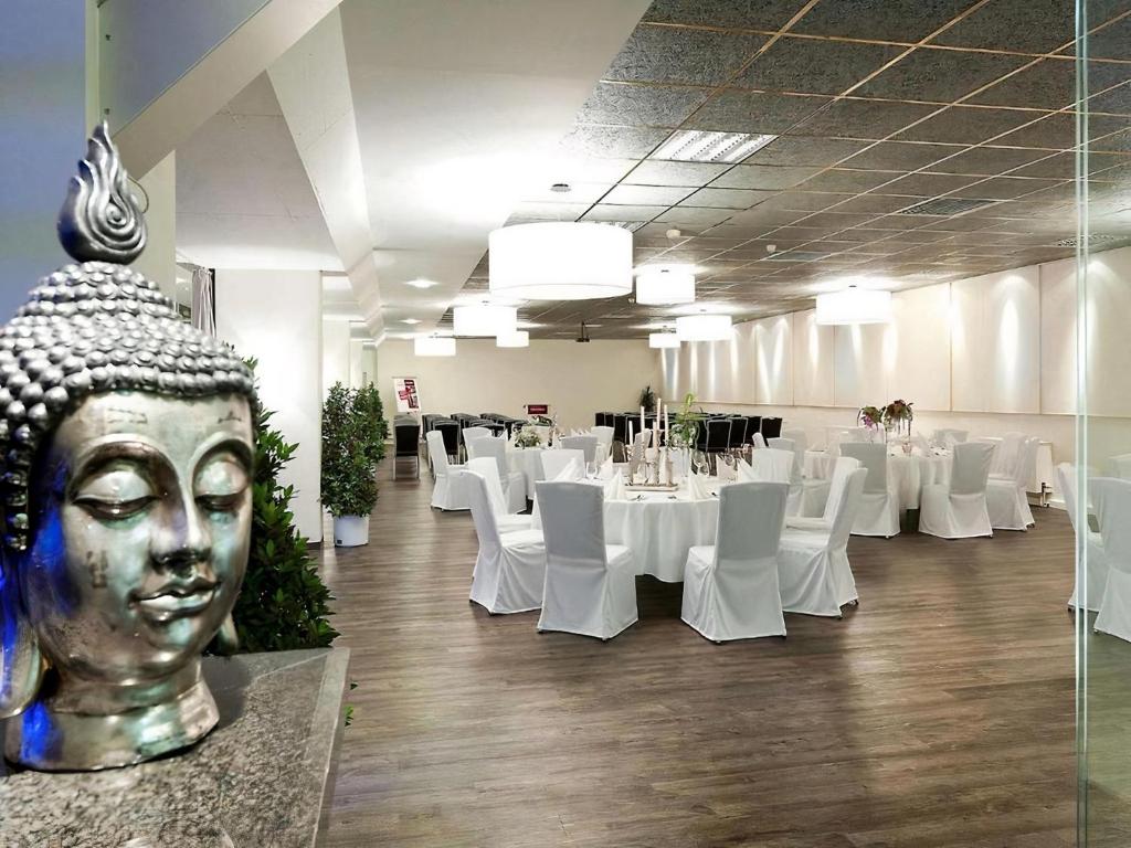 a banquet hall with white tables and a large statue at PLAZA INN Regensburg in Regensburg
