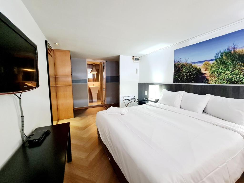 a bedroom with a large white bed and a flat screen tv at Somewhere to Escape - Hometel in Bangkok
