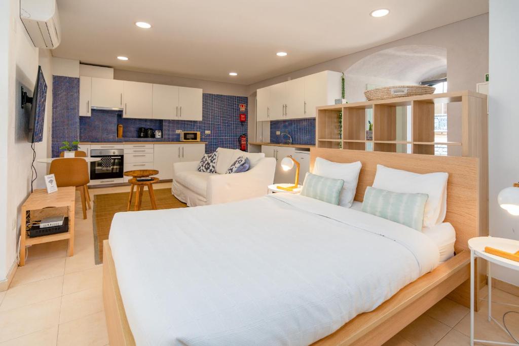 a bedroom with a large bed and a kitchen at Setúbal Downtown Blue in Setúbal