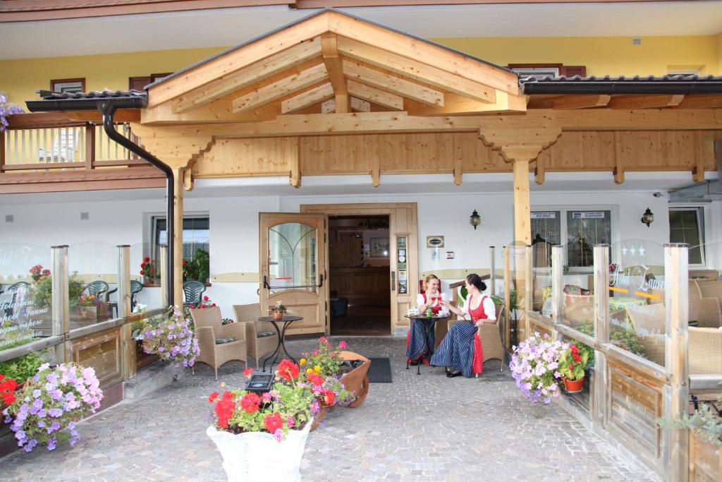 two people sitting at tables under a pavilion with flowers at Hotel Zanon in Ziano di Fiemme