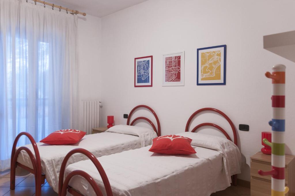 two beds in a white room with red pillows at Ca' Eli 2 in Oliveto Lario