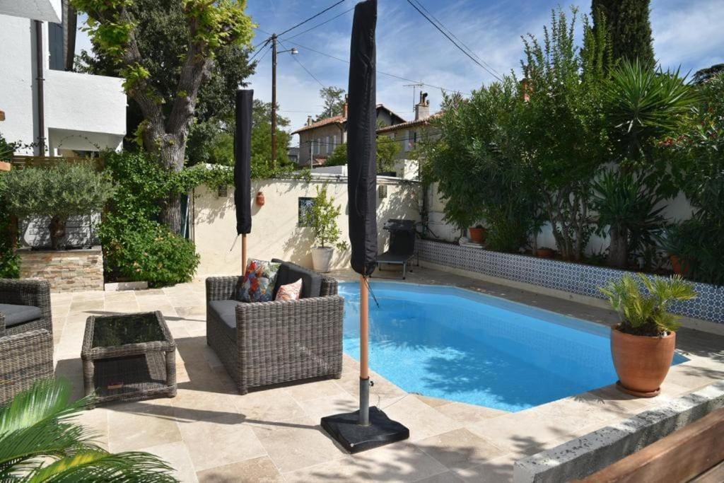 basen na dziedzińcu z krzesłami i parasolem w obiekcie Rez de chaussée de Villa Marseille 9ème w Marsylii