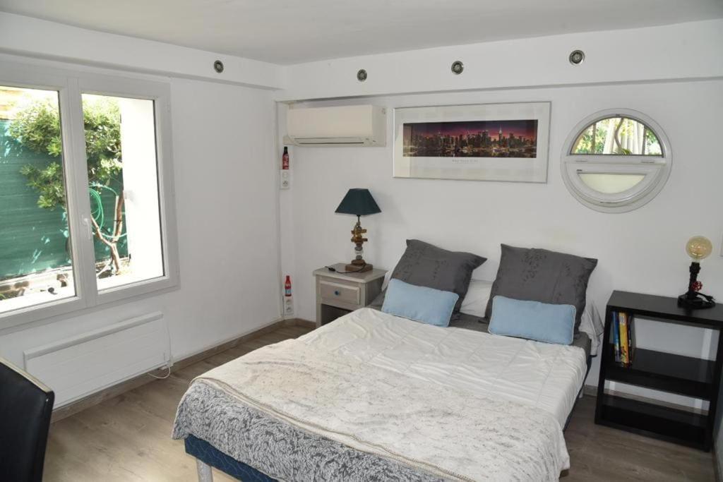 biała sypialnia z łóżkiem i dwoma oknami w obiekcie Rez de chaussée de Villa Marseille 9ème w Marsylii