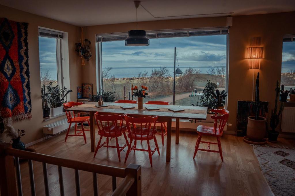 een eetkamer met een tafel en stoelen en een groot raam bij Privatsvit, havsnära och centralt in Malmö