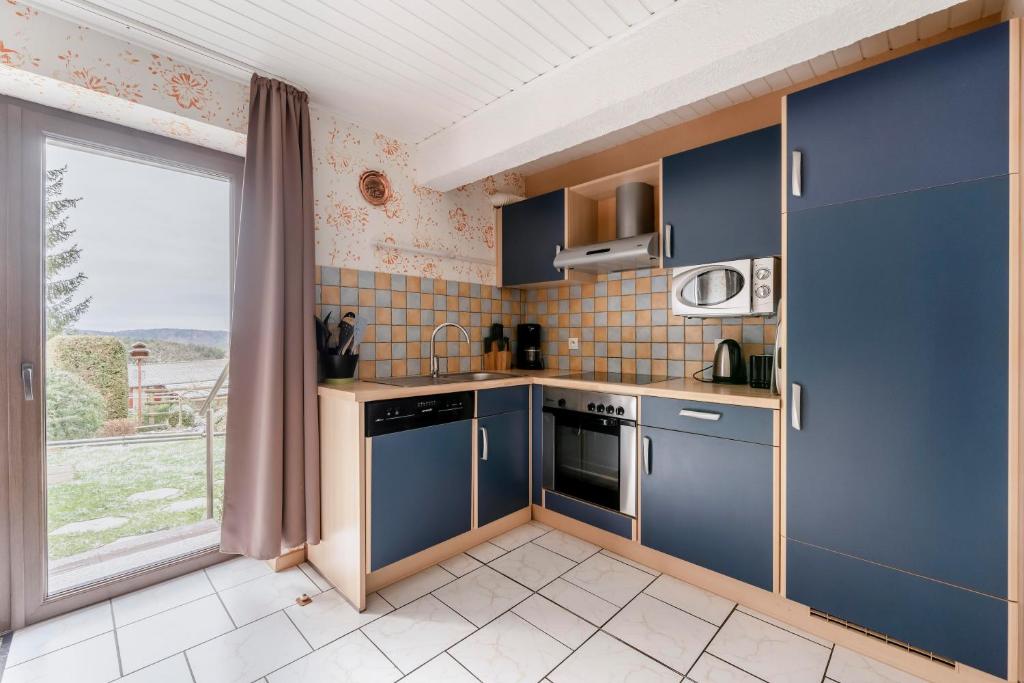 a kitchen with blue cabinets and a large window at Maison de 3 chambres avec jardin clos et wifi a Dabo in Dabo