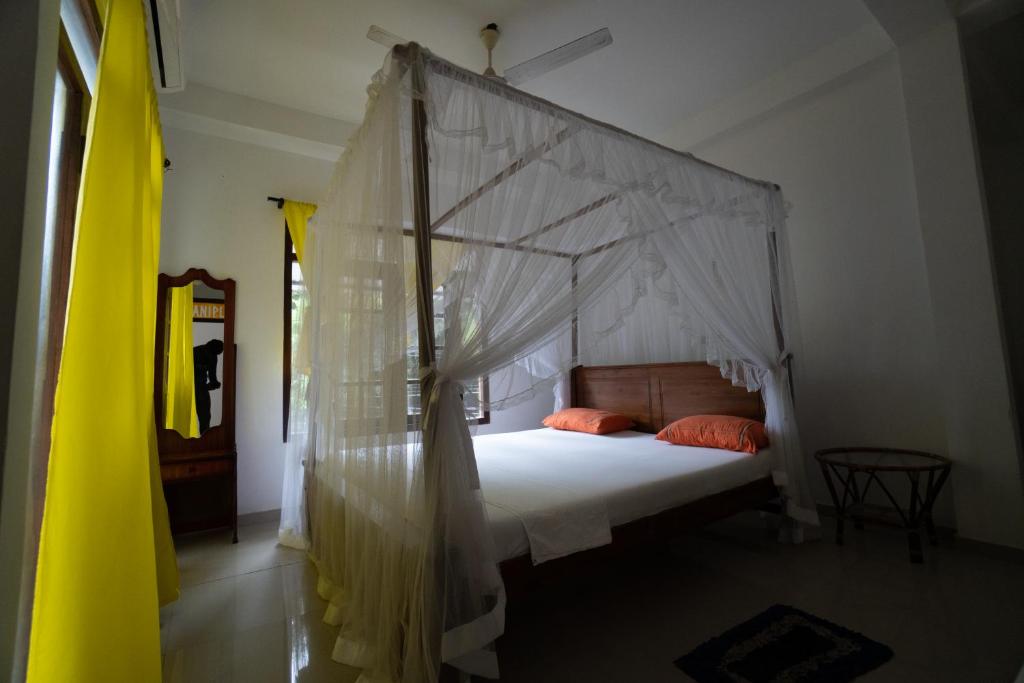 - une chambre avec un lit à baldaquin et des oreillers orange dans l'établissement Happy Rest By Chill House, à Unawatuna