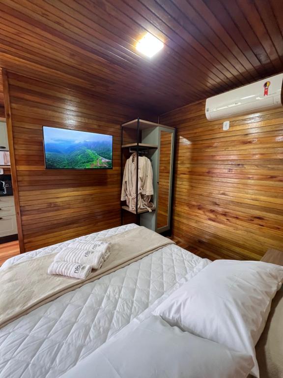 um quarto com uma cama e uma televisão numa parede de madeira em Recanto da Maju em Bom Jardim da Serra