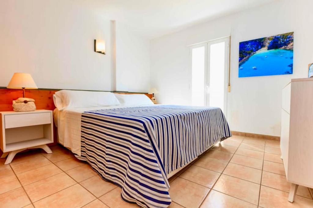 Un dormitorio con una cama con una manta a rayas. en APARTAMENTOS SA VARADERO FRONTE MAR ESPUJOLS, en Es Pujols