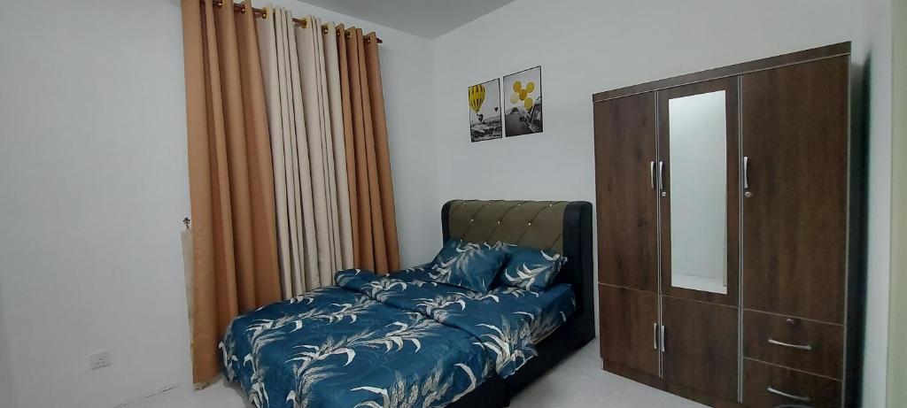 a bedroom with a bed and a dresser and a mirror at Myrol Homestay Kulim in Kulim
