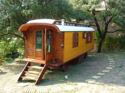 un pequeño vagón de tren amarillo sentado en un patio en Idyllic Roulotte, en Les Assions